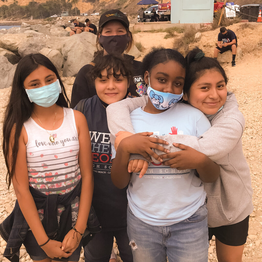 Group of students from We The People High School wearing masks, posing together during an outdoor excursion with a scenic backdrop.